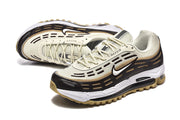 Pair of cream, black, and gold-tone Nike Air Max 97 OG sneakers in a three-quarter view.