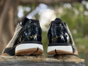 Rear view showing glossy black heel panels, white midsole sections, and gold-colored signature detailing.