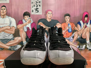 Front view of white and black lace-up sneakers with black uppers, white toe panels, and metallic details.