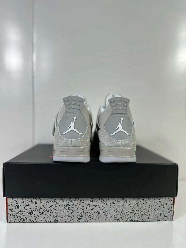 Rear view of a light grey Air Jordan 4 pair displayed on a speckled shoebox.