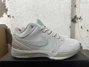 Side view of a light grey basketball shoe with a Swoosh, lace-up closure, and Kobe-inspired signature detail.
