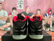 Rear view of black Nike sneakers with red lining, glossy uppers, and pale translucent soles.