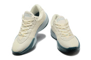 Pair of cream Nike G.T. Cut Academy basketball shoes with pale blue accents, shown from the front.