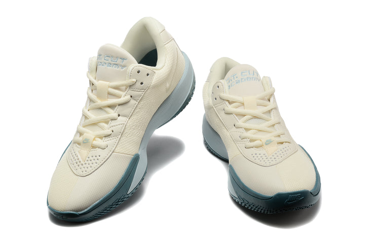 Pair of cream Nike G.T. Cut Academy basketball shoes with pale blue accents, shown from the front.