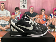 Side view of a black and white basketball sneaker showing the textured upper, white Nike swoosh, white heel panel, and gold number 2.