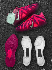 Pink and purple sneakers shown with loose laces and separated white sole components.