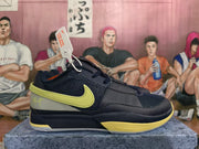 Side view of a navy basketball shoe with a yellow Swoosh and gray heel panel