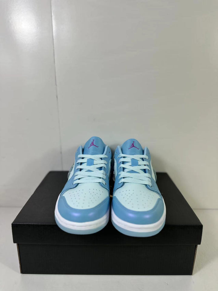Front view of blue and light blue low-top sneakers with white laces on a black shoebox.