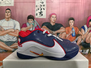 Side view highlighting the white midsole area, navy blue upper, red trim, and gold-toned side swoosh.