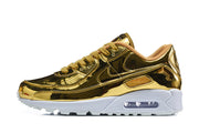Side view of a gold-tone Nike Air Max 90 QS sneaker with white midsole and visible Air unit.