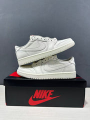 Two white low-top Jordan sneakers stacked on a shoe box, showing the side panels, perforated toe boxes, and rubber outsoles.