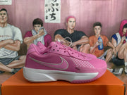 Side view of a pink Nike basketball sneaker showing the swoosh, Air Zoom text, white midsole, and textured outsole.
