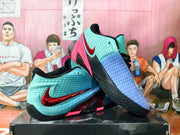 Nike basketball shoes displayed at an angle, showing the aqua and blue upper, red accents and textured black outsole.