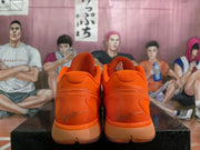 Rear view of a pair of bright orange Nike basketball sneakers showing padded collars, sculpted heels, and gum-toned outsole sections.