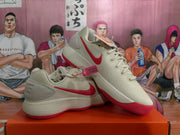 Angled view of a pair of white Nike sneakers with red Swooshes, light-colored laces, and red outsole accents.