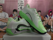 Angled side view of green and grey Jordan basketball sneakers showing the layered black side detail and lace-up design.