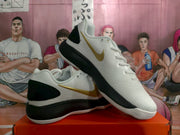 Angled view of the pair highlighting the gold side swoosh, white uppers, black heel sections, and layered soles.