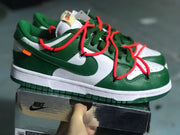 Side view highlighting the green overlays, white midsole, red laces, and orange accent tab.
