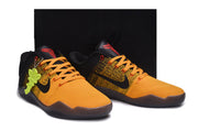 Orange and black basketball shoes displayed in front of a black box