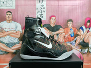 Side view of a black and multicolor high-top basketball sneaker with white side branding, a patterned ankle panel, and a white outsole.