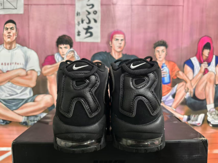 Rear view of black Nike sneakers showing white Swoosh logos, padded collars, and transparent sole cushioning details.