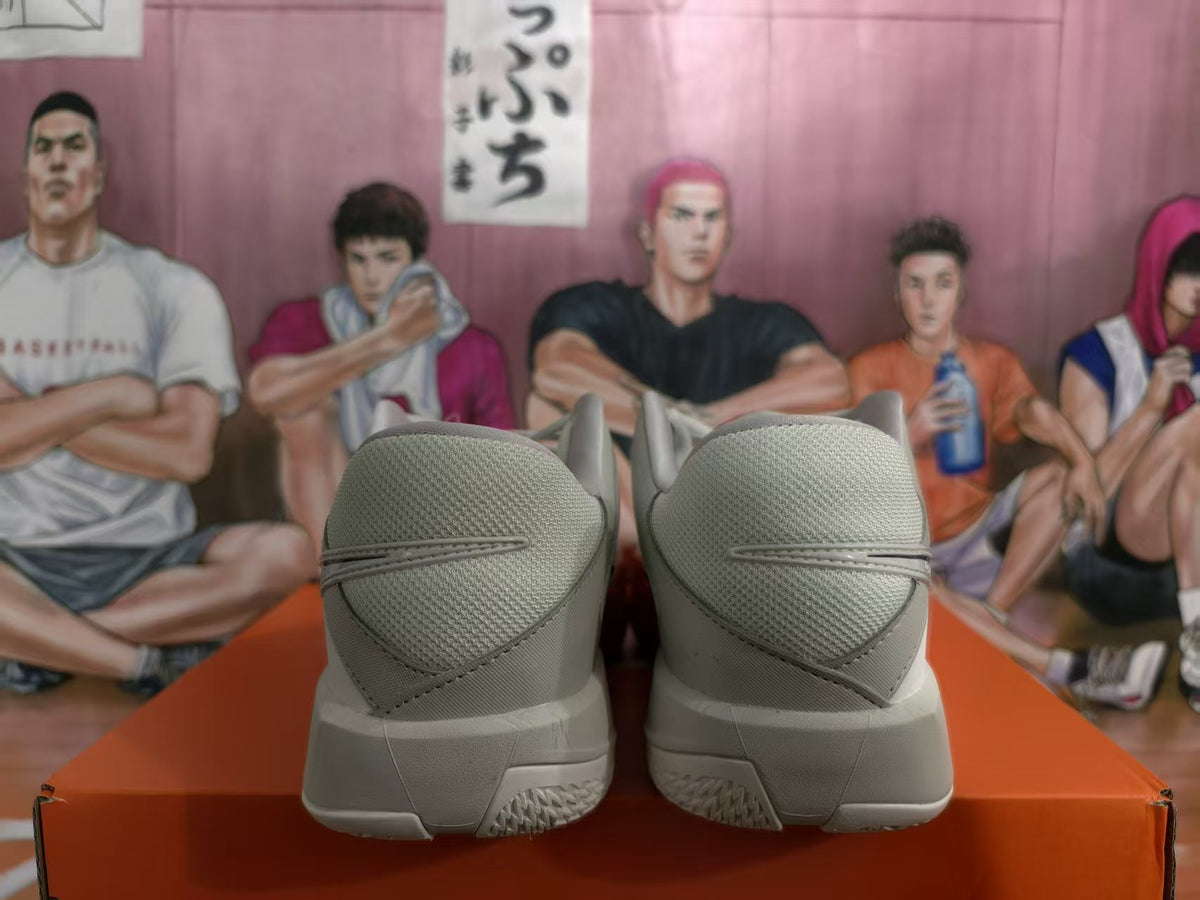 Rear view of gray Nike basketball sneakers with red outsole accents on an orange shoebox.