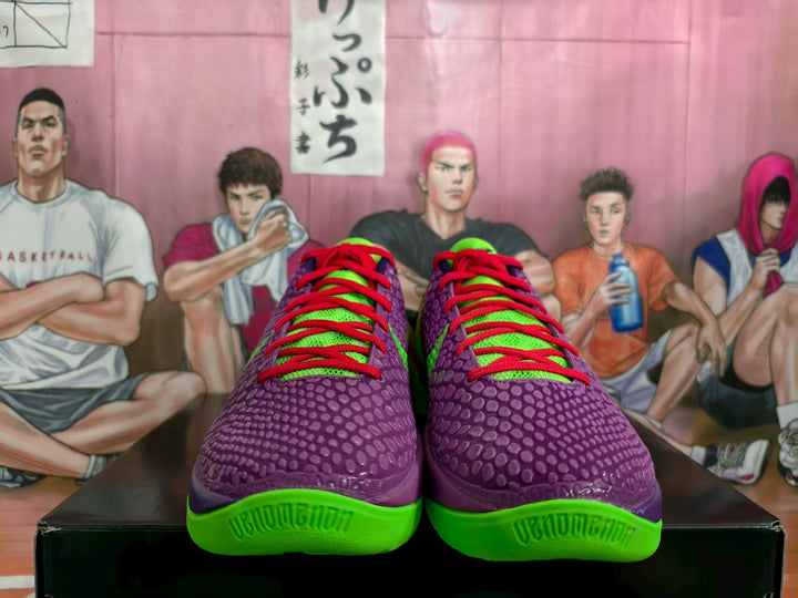 Front view of purple and green Nike basketball sneakers with red laces on a black shoebox.