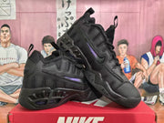 Angled view of black Nike sneakers showing layered panels, purple side accents, laces, and sculpted soles.