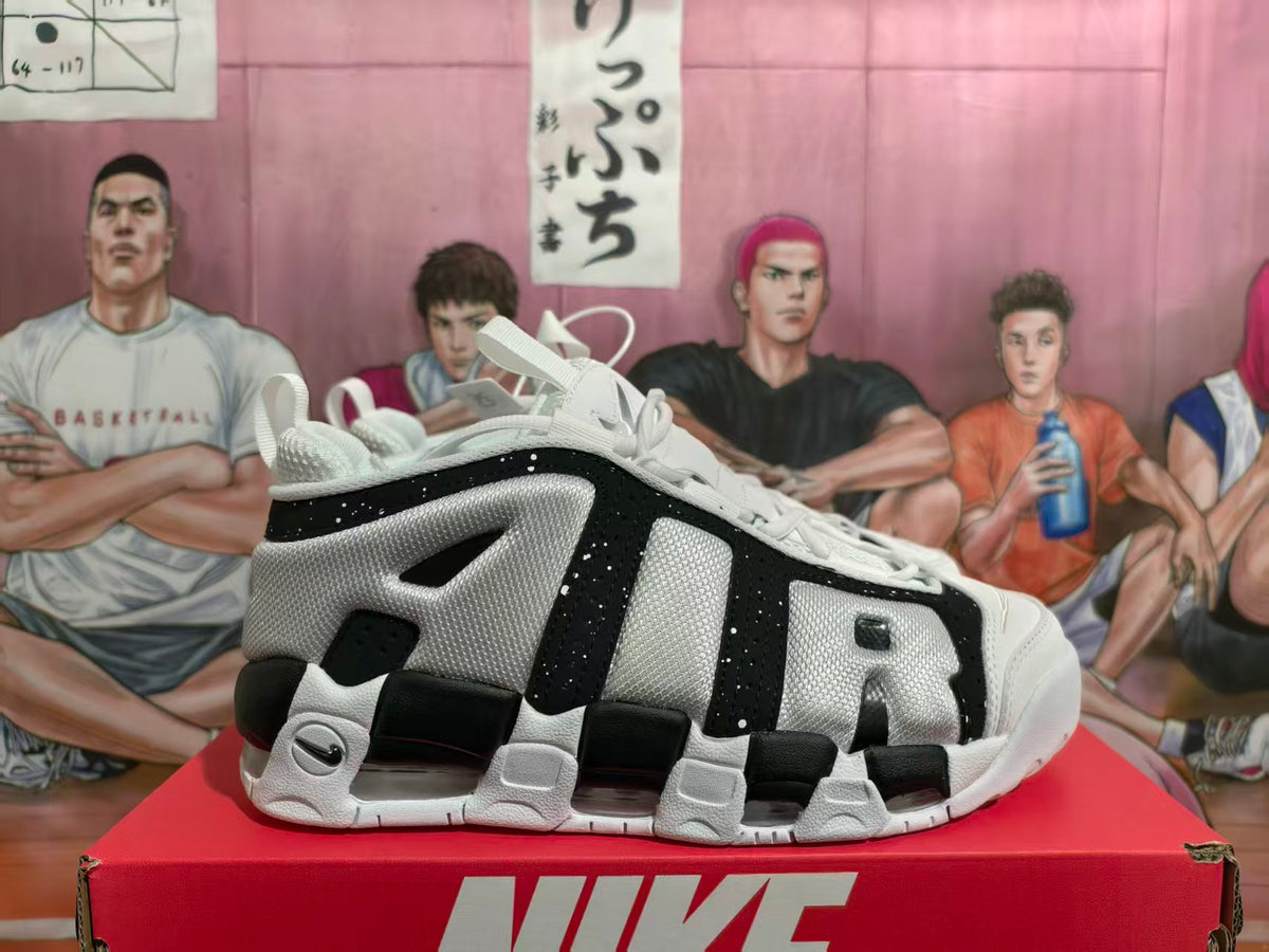 Side view of white, black, and grey Nike Air More Uptempo sneakers with oversized AIR lettering.