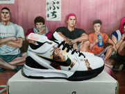 Side view highlighting the black swoosh, gold detailing, graphic artwork, and layered white midsole.