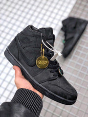 Black high-top sneaker held in hand with visible tongue branding and decorative hangtag.