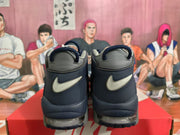 Rear view of navy and gray Nike high-top sneakers showing contrasting heel Swoosh branding and visible air units.