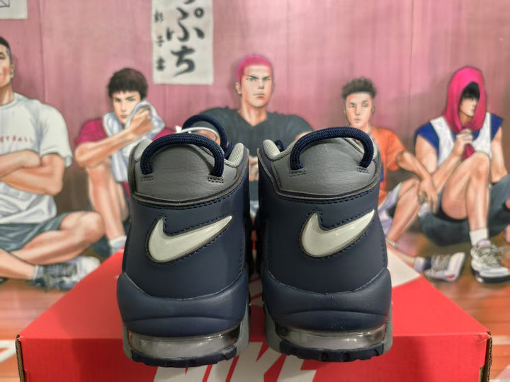Rear view of navy and gray Nike high-top sneakers showing contrasting heel Swoosh branding and visible air units.