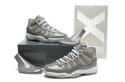 Pair of gray and white sneakers displayed with a dark shoe box and gray display forms.