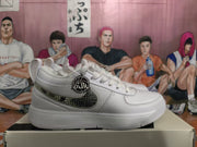 Side profile of a white sneaker showing the dark patterned swoosh and circular side accessory.