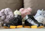 Front view of the pair showing black uppers, ankle straps, and yellow outsoles.