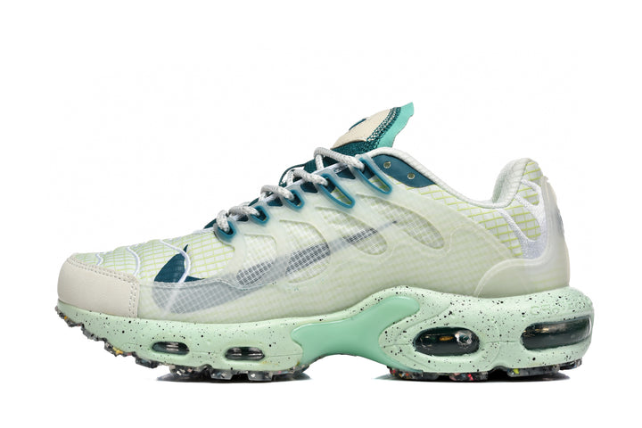Side view of a white Nike Air Max Plus sneaker with mint-green and blue-green accents and a speckled sole.