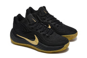Pair of black Nike sneakers with gold branding and gum-colored outsoles shown from a front three-quarter angle.