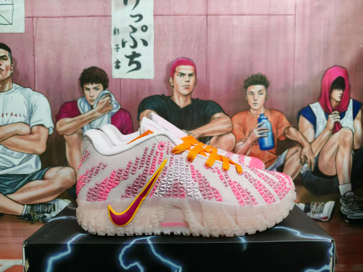 Side view of white Nike sneakers with pink textured detailing, orange laces, and a pink-and-yellow Swoosh on a black box.