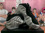 Angled product view showing the silver textured upper, black accents, reflective Swoosh, and translucent outsole.