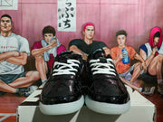 Front view of black glossy sneakers with white laces, patterned uppers, and white outsole sections.