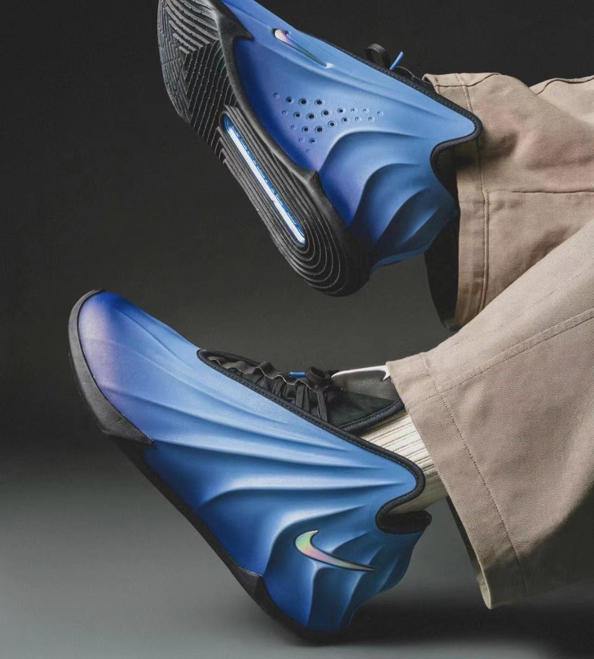 Pair of blue Nike sneakers with sculpted uppers, black trim, black soles, and contrasting Swoosh branding shown on a model.