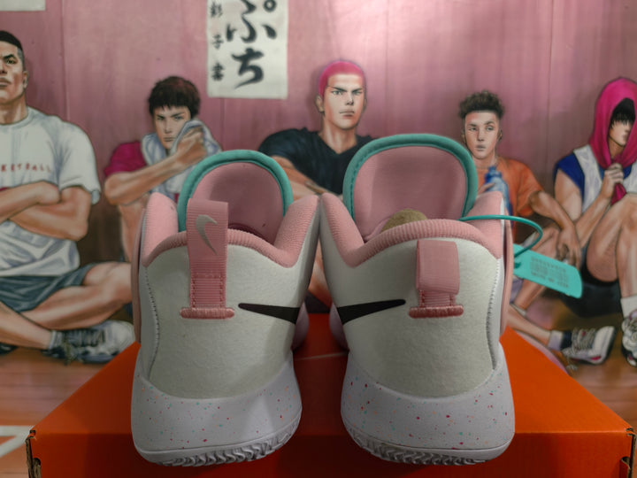 Rear view of white Nike basketball shoes with pink heel details and speckled outsoles