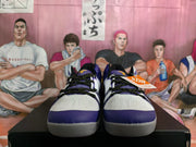 Front view of white basketball shoes with purple toe accents and black laces.