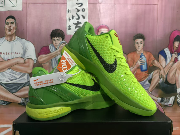 Pair of neon green Nike basketball sneakers displayed on a black shoebox, showing black Swoosh logos, textured uppers, red accents, and a visible Zoom-marked midsole.