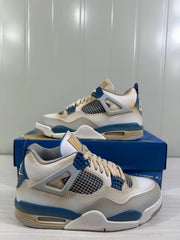 Pair of white and blue Jordan Air Jordan 4 Retro sneakers shown from the side on a blue shoebox.
