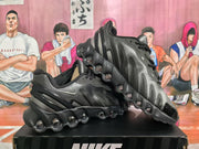 Angled view of a pair of black and silver Nike sneakers highlighting the layered upper and visible circular outsole elements.