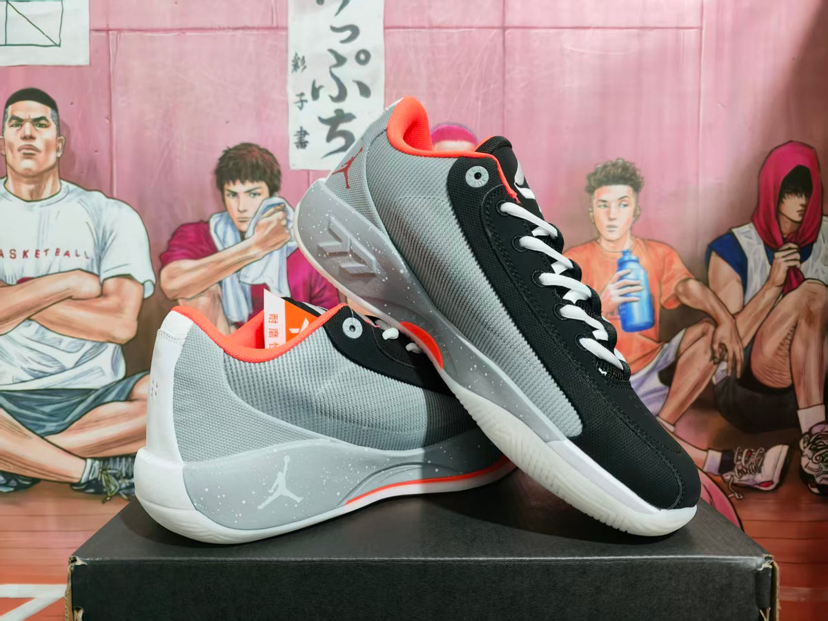 Pair of black and gray Jordan basketball sneakers displayed on a box, showing the side profiles and speckled gray midsoles.