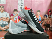 Pair of black and gray Jordan basketball sneakers displayed on a box, showing the side profiles and speckled gray midsoles.