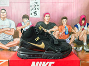 Side view of black Nike high-top sneakers with gold Swoosh, raised AIR detailing, and midfoot strap